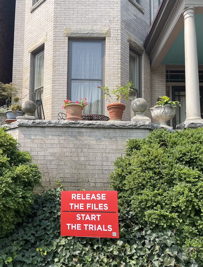 Supporter holding a Release the Files yard sign