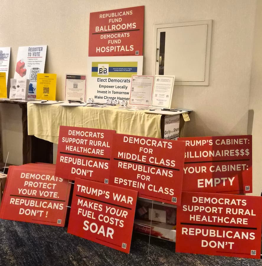 Factocracy signs displayed on a table alongside voter registration materials at the Women's Summit