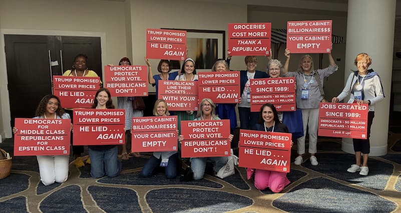 Group of women at the Women's Summit holding up an array of Factocracy signs
