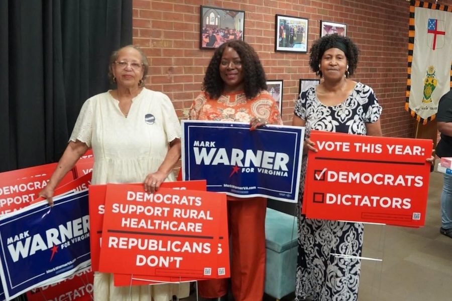 Vote This Year, Healthcare, and Mark Warner campaign signs held at an event